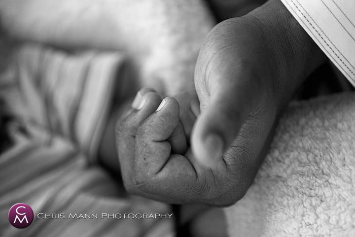 father holds his baby's hand in his