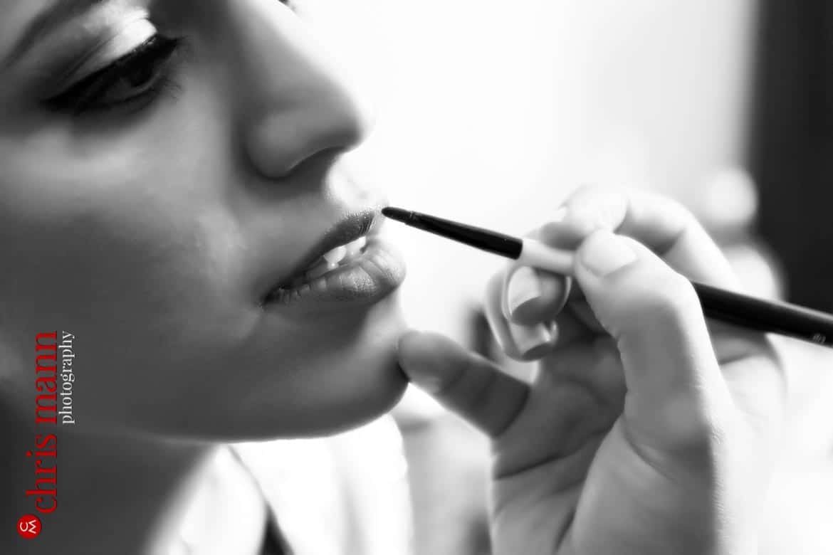 makeup artists applies lipstick to bride