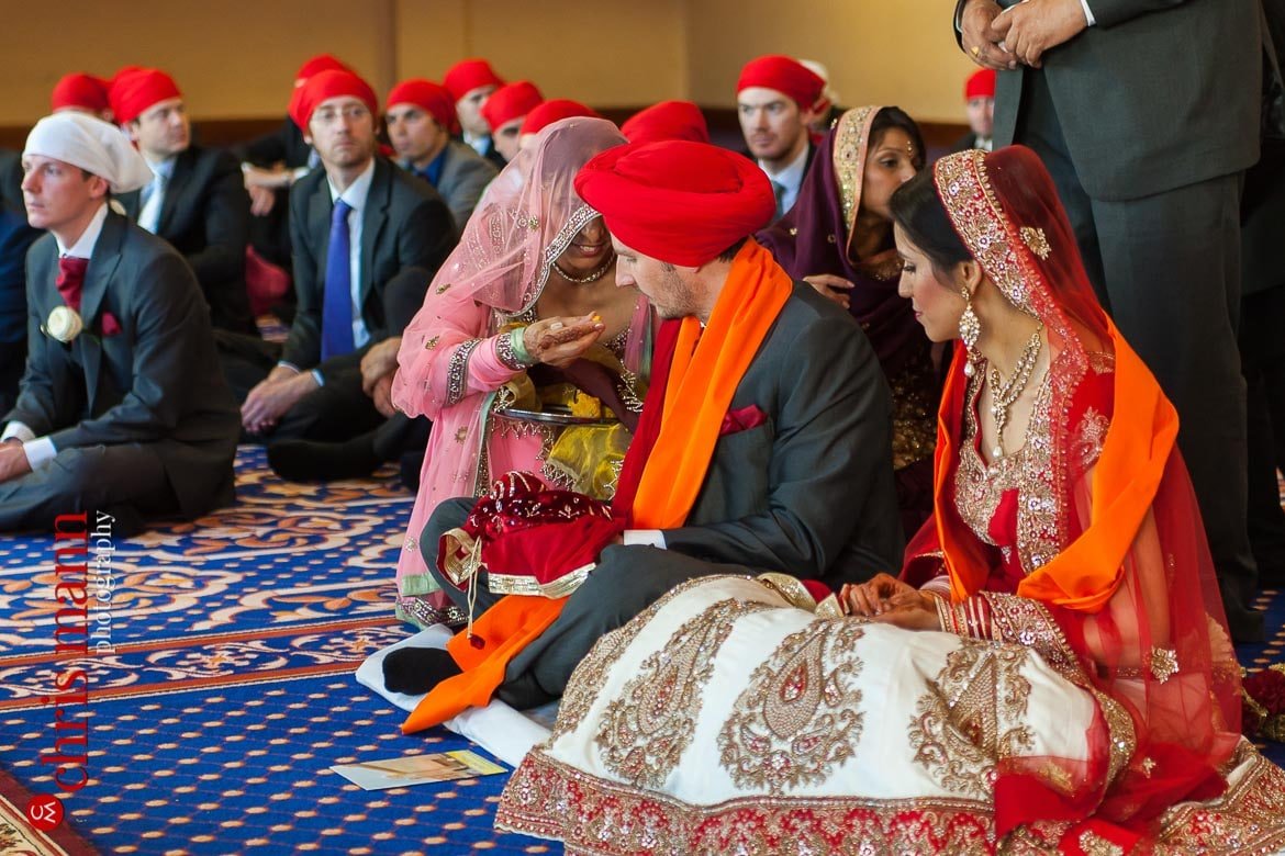 mother of bride feeds groom at Sikh wedding ceremony
