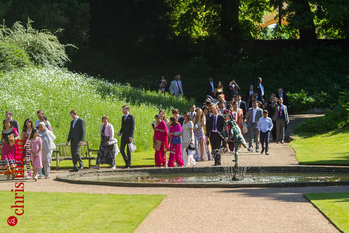 wedding guests walk through gardens to reception at reception Syon Park Great Conservatory