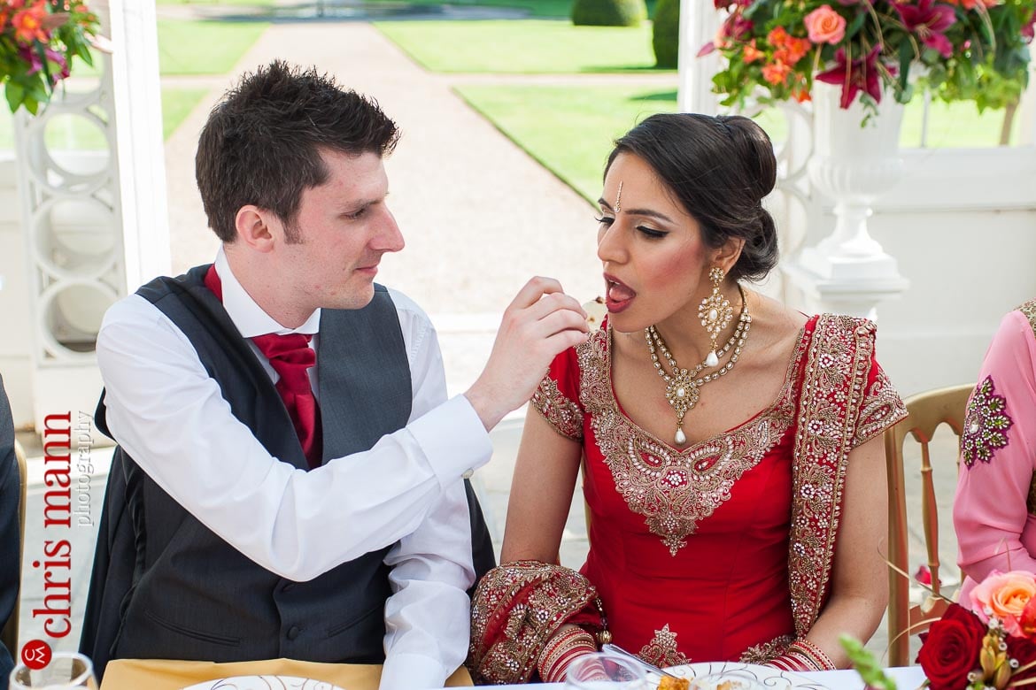 groom feeds bride wedding breakfast at reception Syon Park Great Conservatory