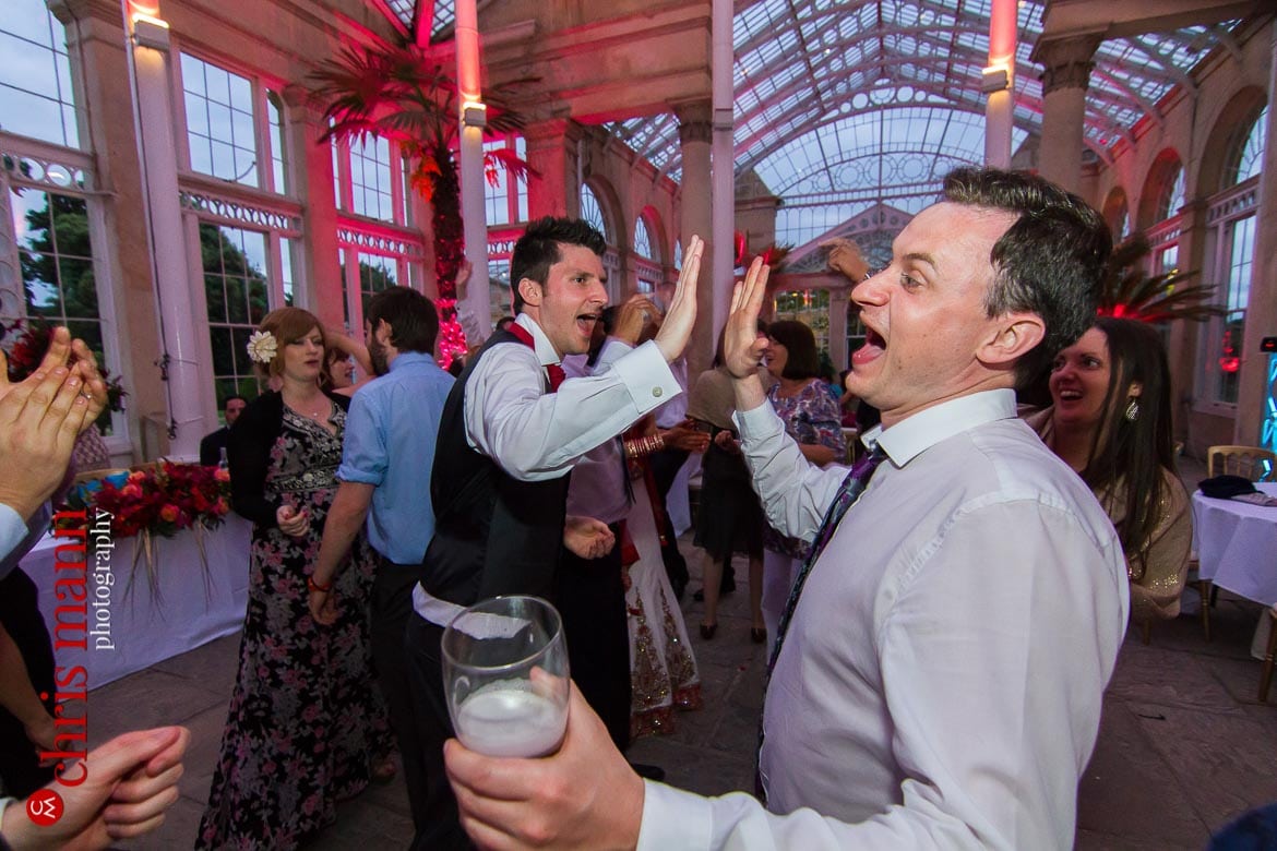 groom high fives with guest at reception Syon Park Great Conservatory