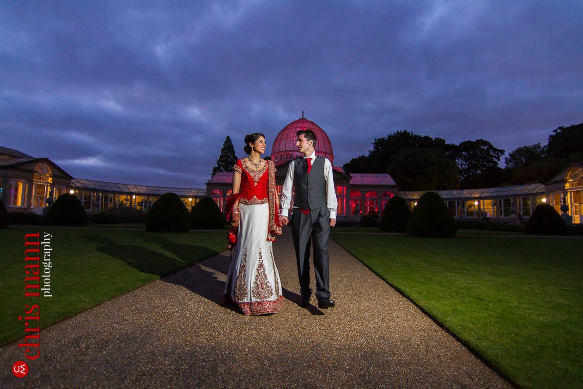 bride and groom walk in gardens at dusk Syon Park Great Conservatory