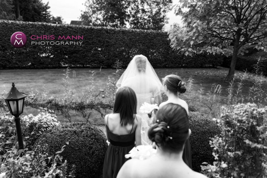 bride and bridesmaids walk through garden on way to wedding