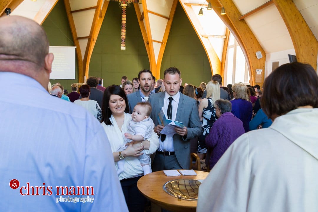 family gather at the font for christening