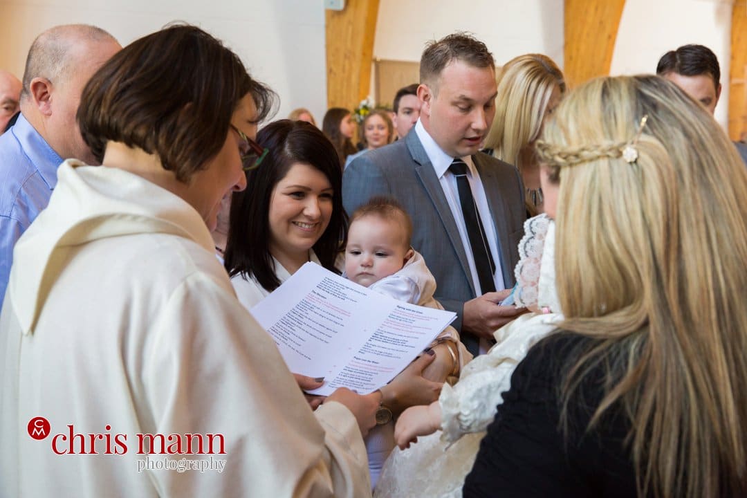 minister reads blessing at font christening