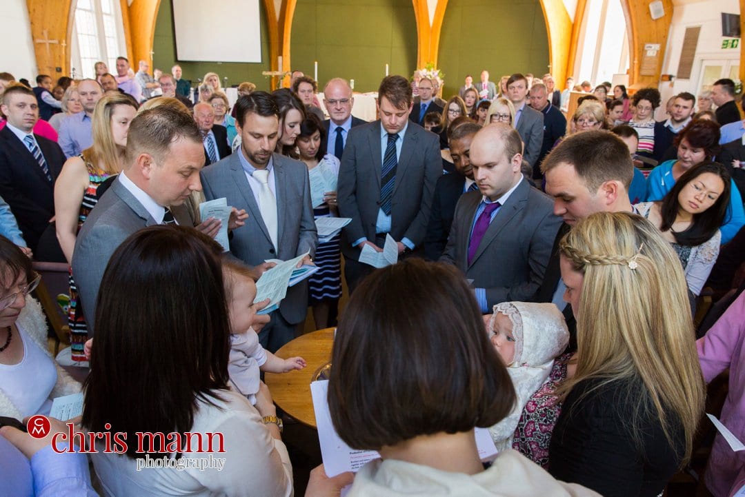 minister and family gather around font