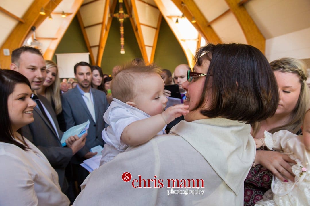 lady vicar holds baby at christening