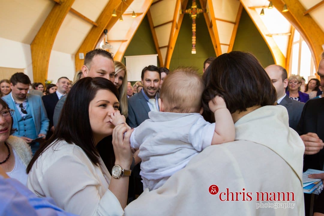 mother kisses baby's hand after christening