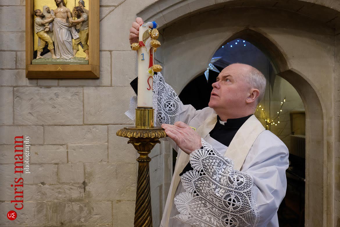 Father Sean Finnegan lights candle at Sacred Heart Church Caterham