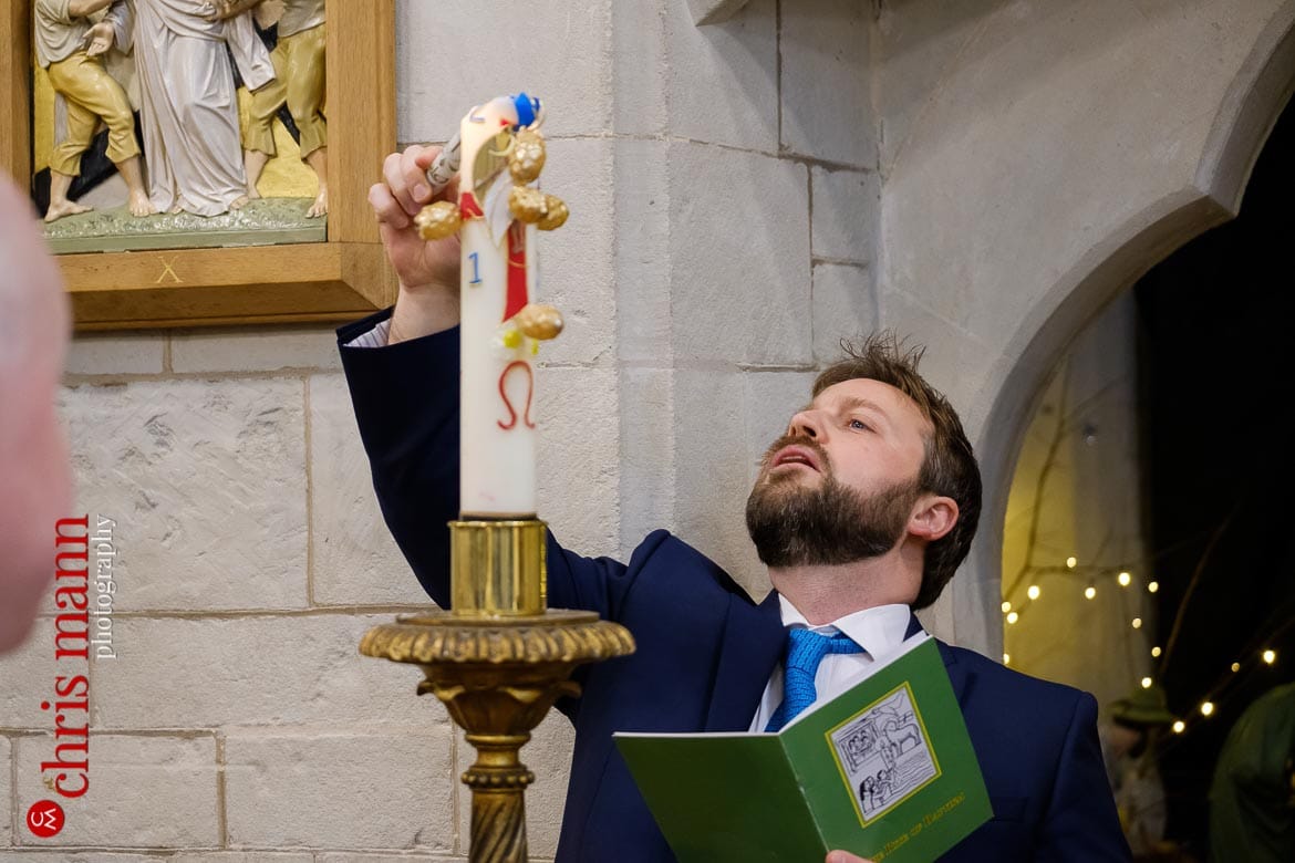 godfather lights candle at baptism ceremony Sacred Heart Church Caterham